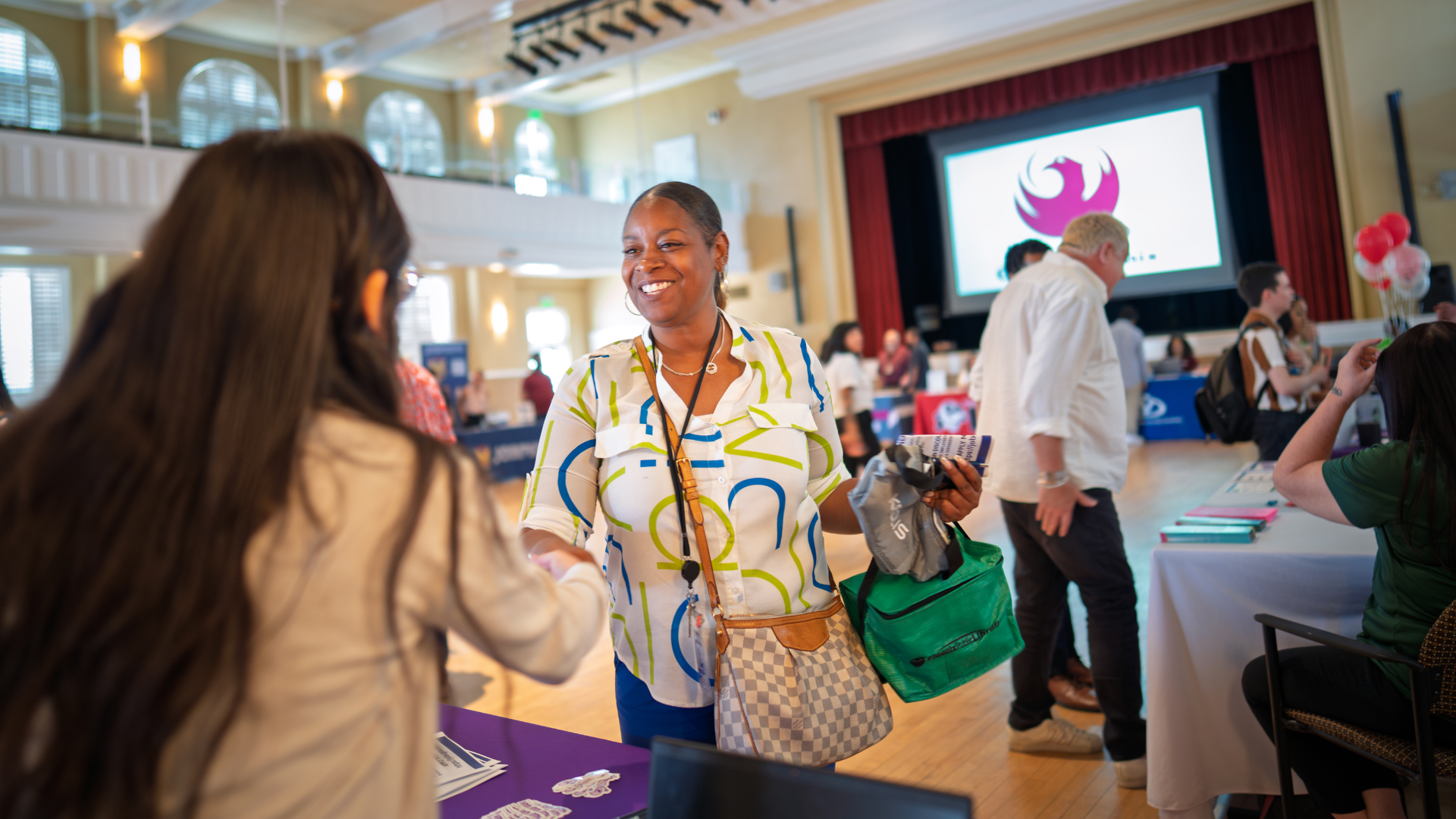A City of Phoenix employee greets a smiling female resident at a resource event